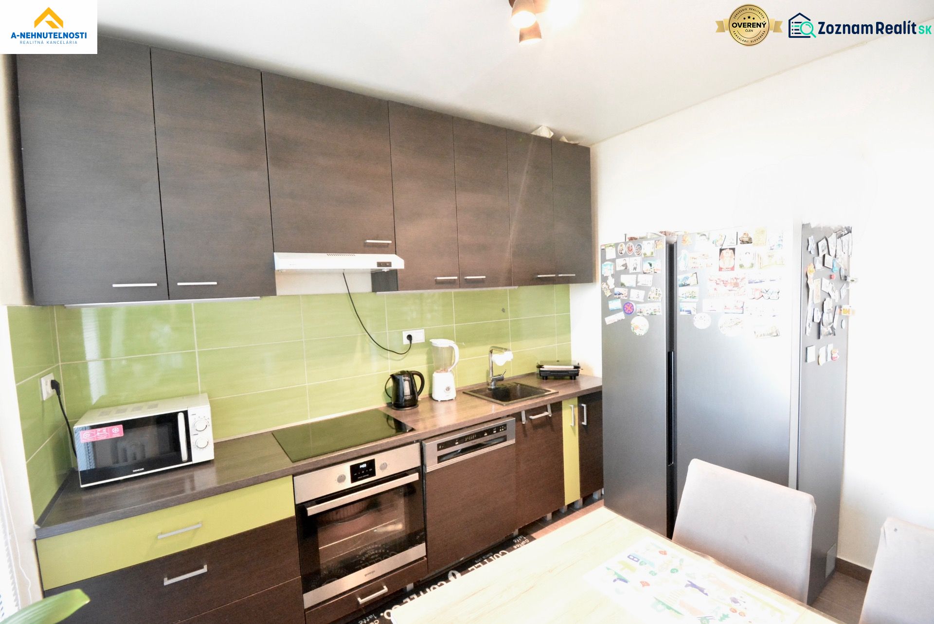 A kitchen with dark cabinets, green tiles, and appliances in a three-room apartment.