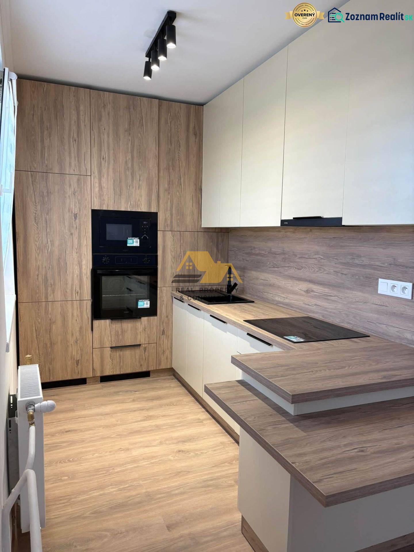 A kitchen in a 2-room apartment with a wooden decor floor and light furniture.