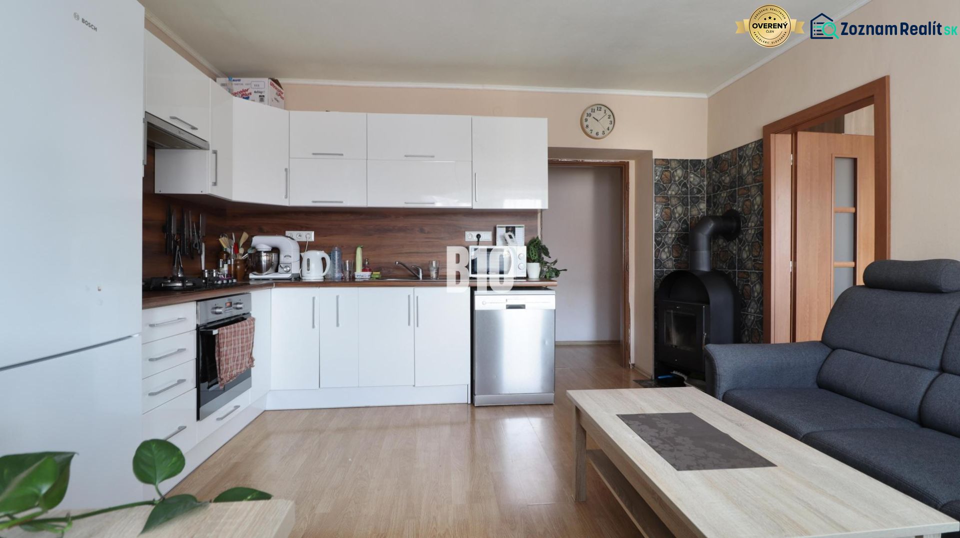 A bright kitchen with white cabinets and a wood-patterned floor in a three-room apartment.