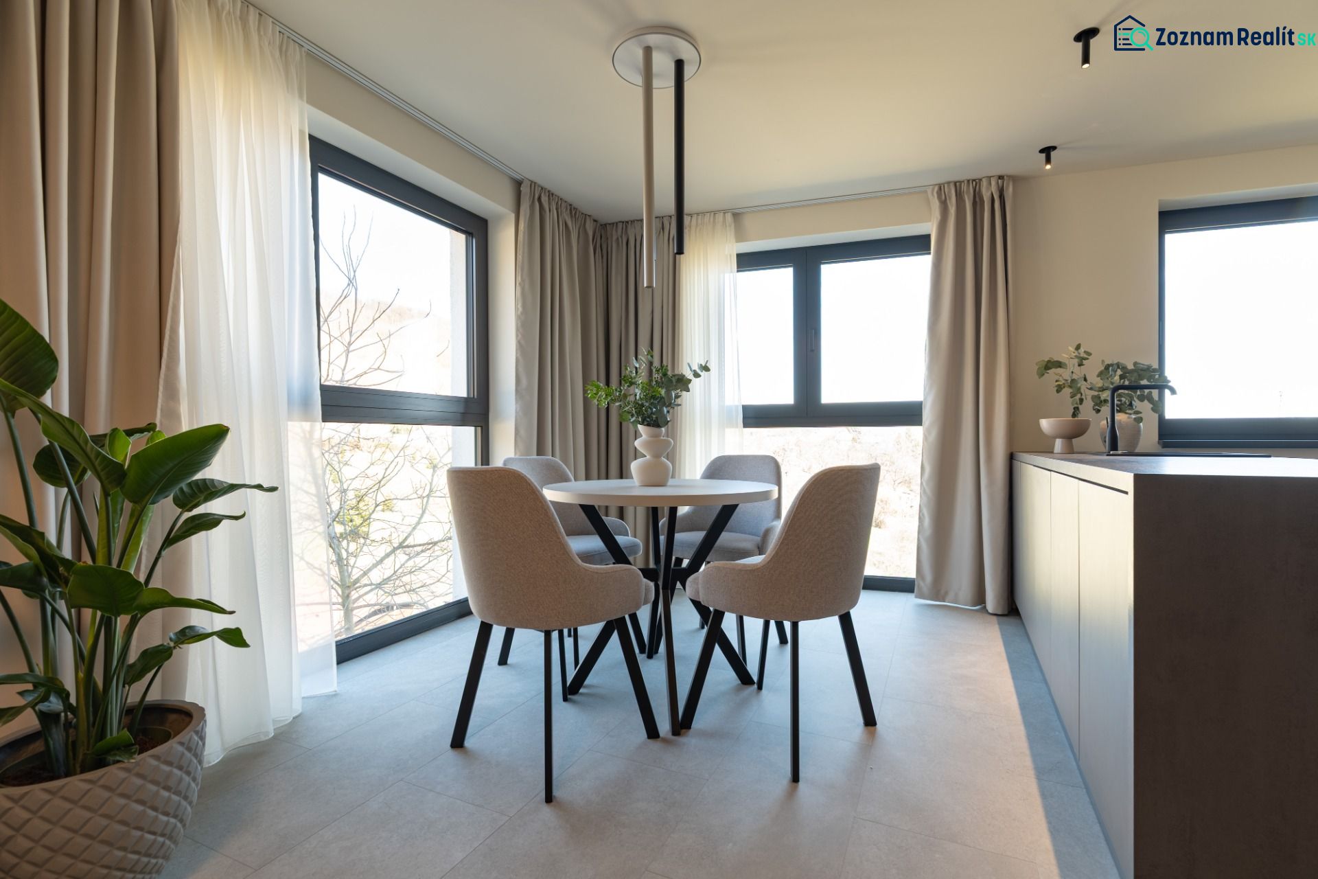 Dining room with a table and four chairs, famous flowers, and curtains in a 4-room apartment.