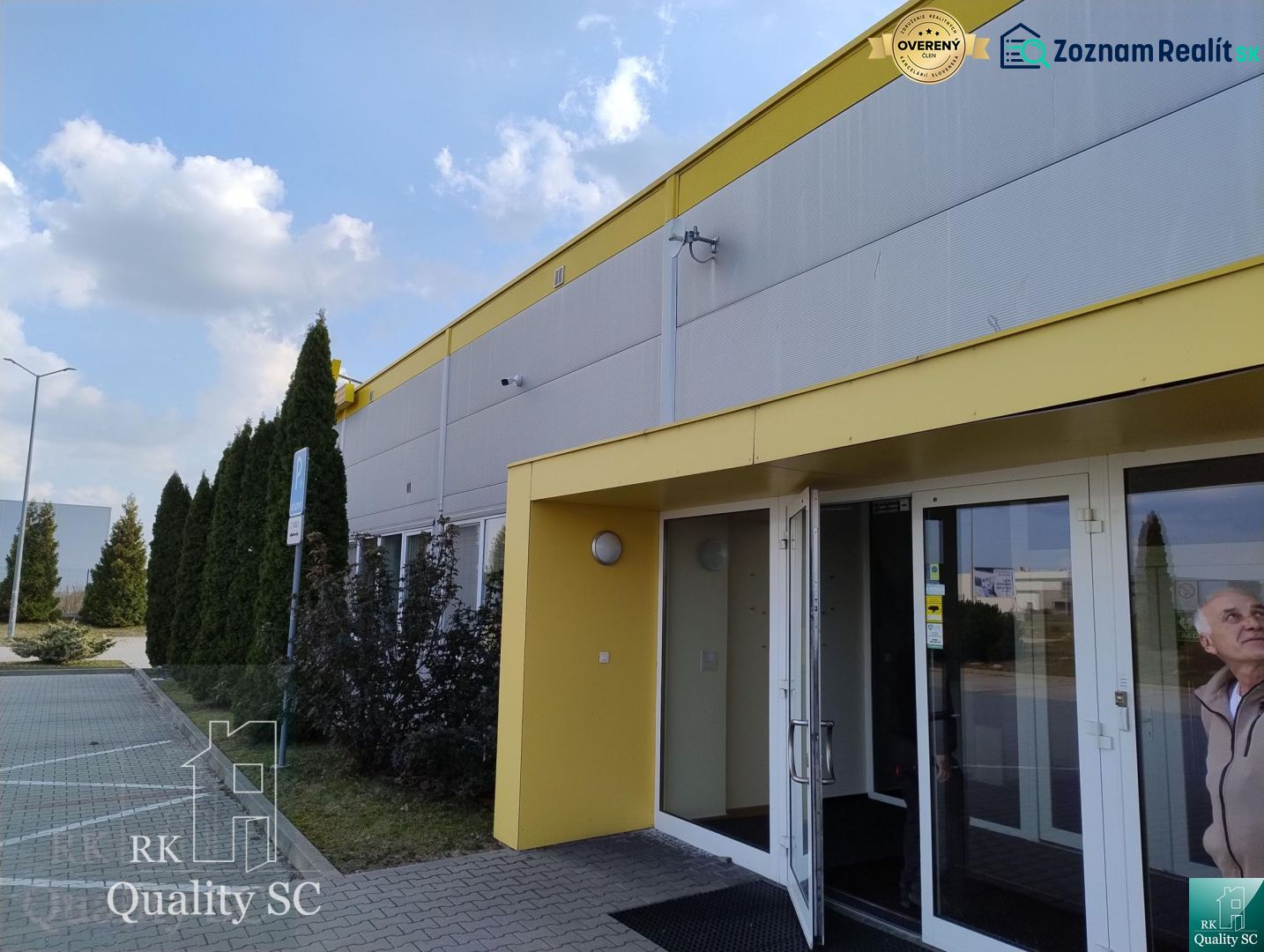 Exterior of a building in Senec with a parking lot and a yellow entrance to the offices.