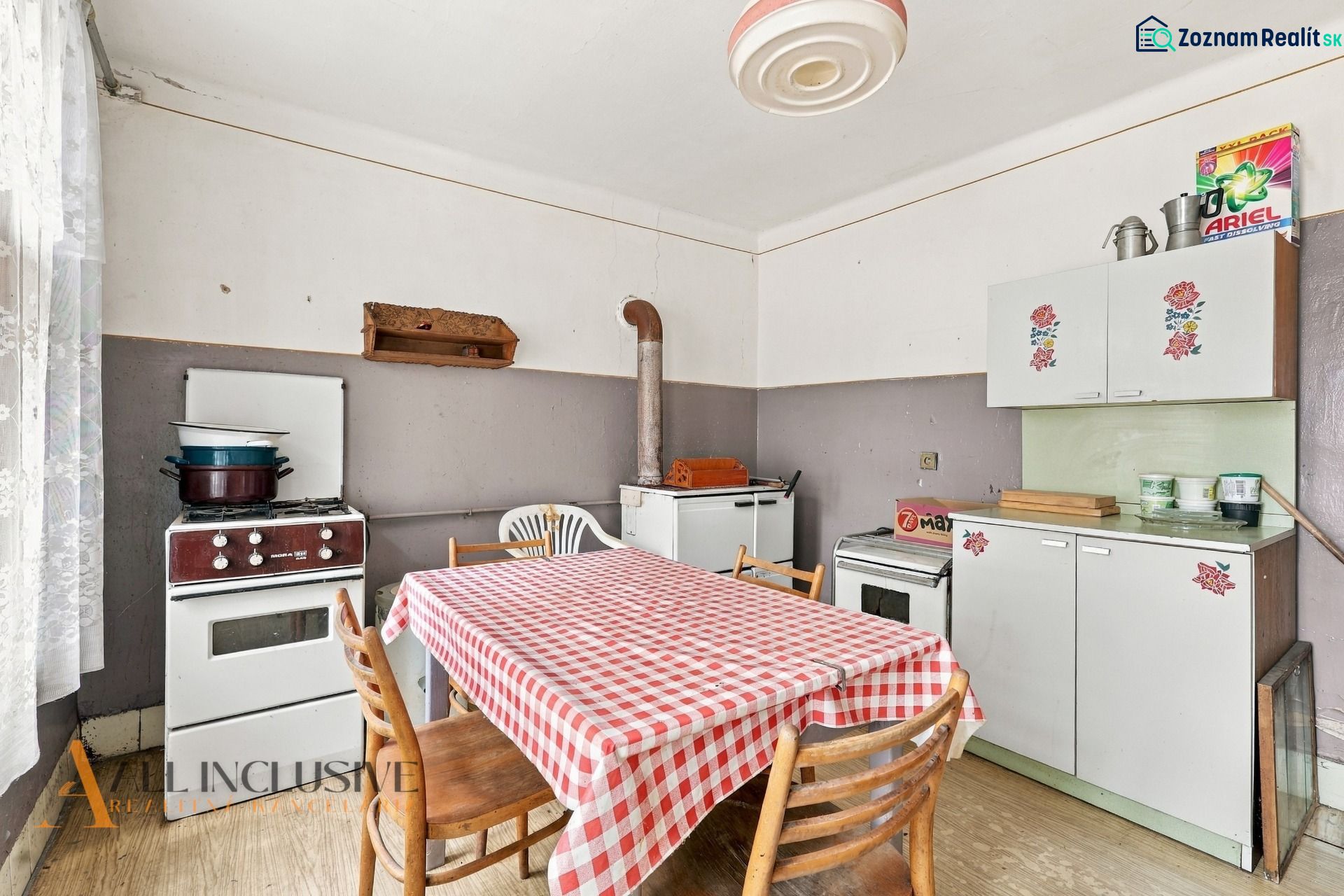 A kitchen in a family house with a kitchen unit, a stove, and a table with a checkered tablecloth.