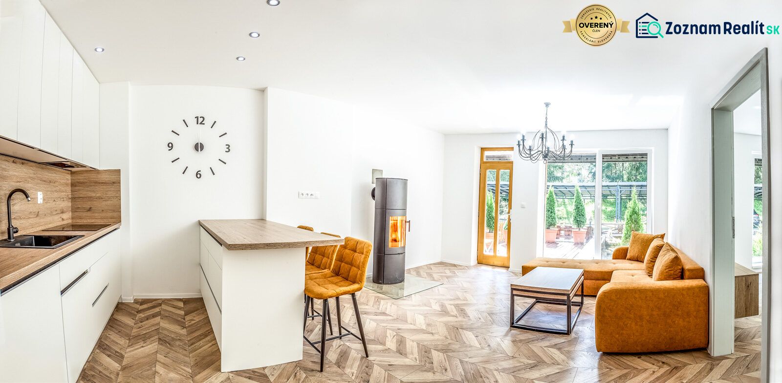 Bright holiday apartment with a kitchen, orange sofa, and wood-patterned flooring.
