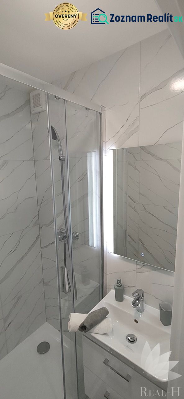 A bathroom with marble-look tiles and a shower in a 3-room apartment.