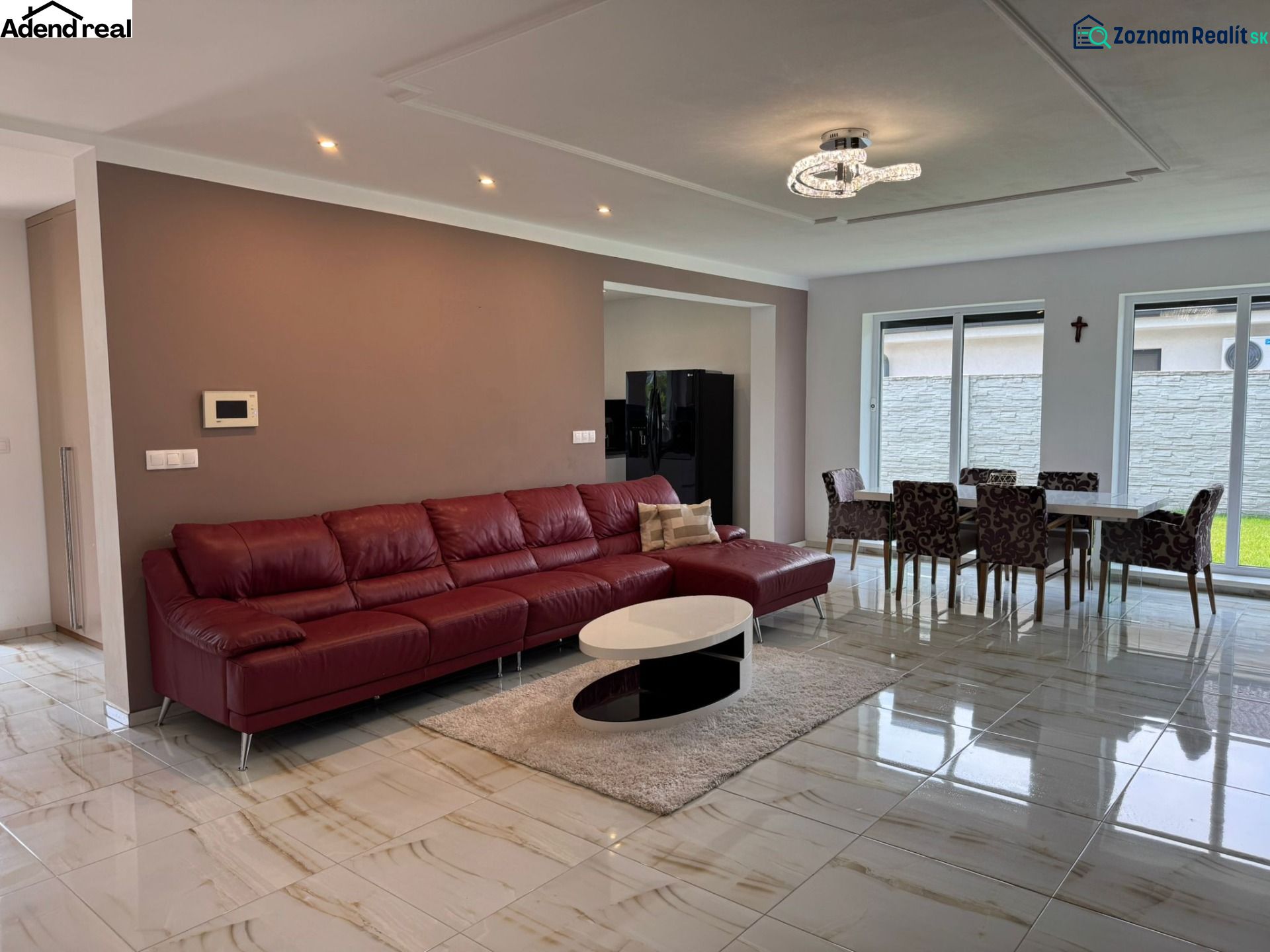 Living room in a family house with a red sofa, dining table, and large windows.