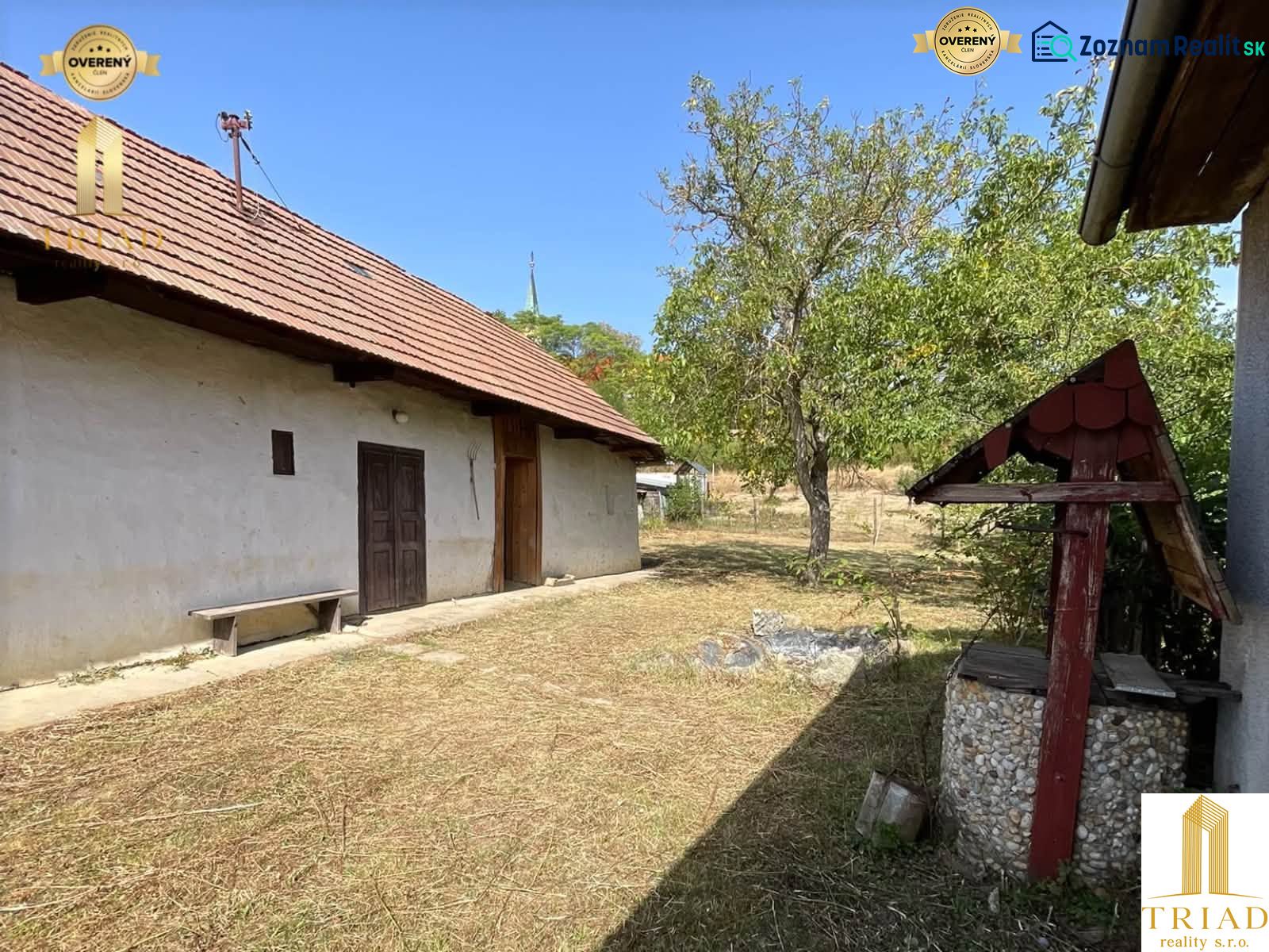 A cottage in Čaka with a grassy yard, trees, and a traditional well.
