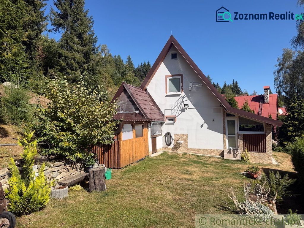 A cottage in the village of Látky surrounded by green trees and a manicured lawn.