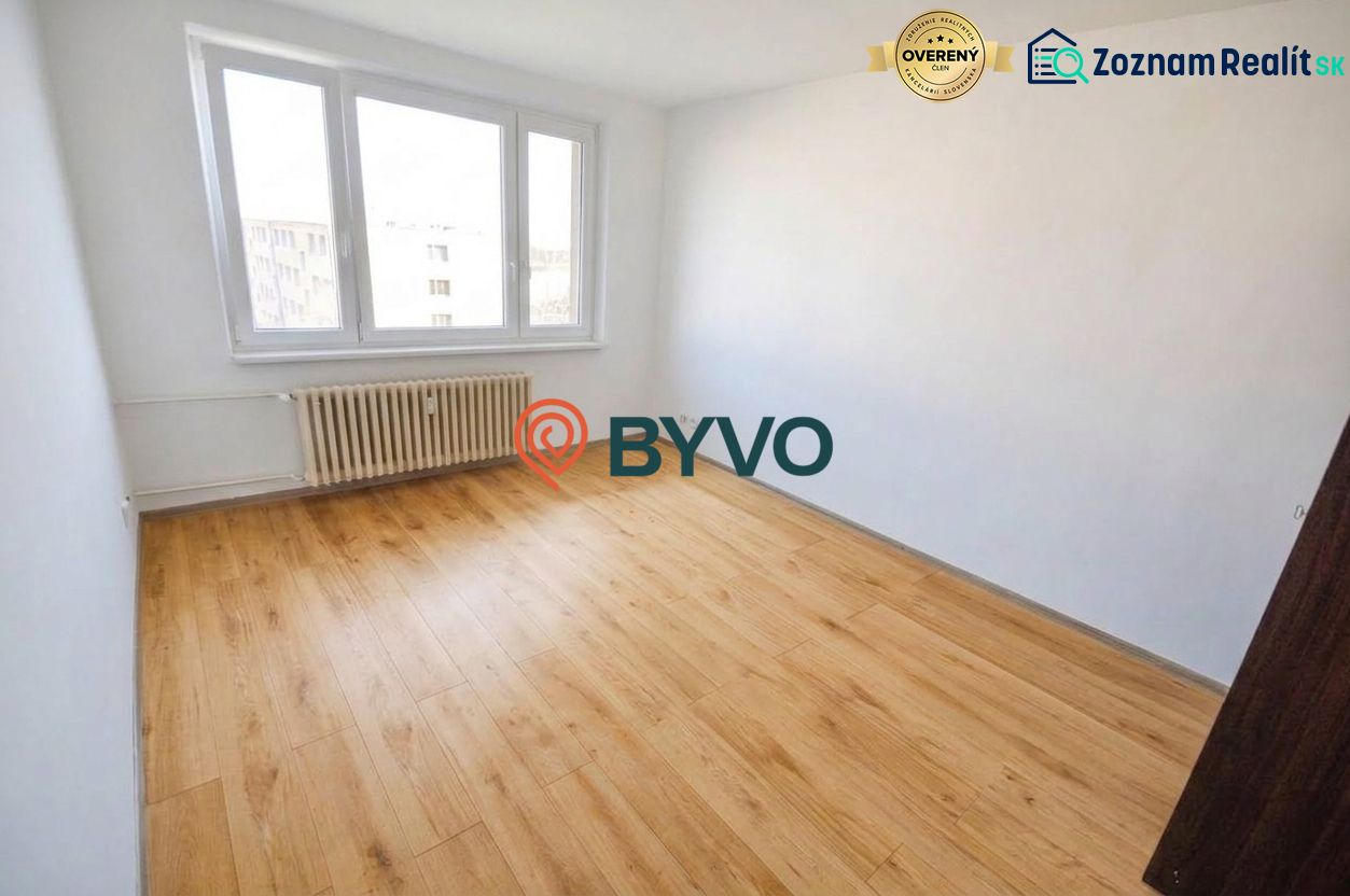 A room in a 2-room apartment with a large window and a floor with a wooden decor.
