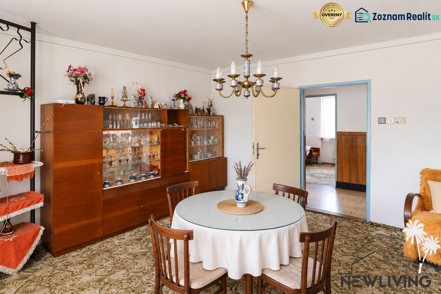 Dining room in a family house with a chandelier, round table, and a display cabinet with glasses.