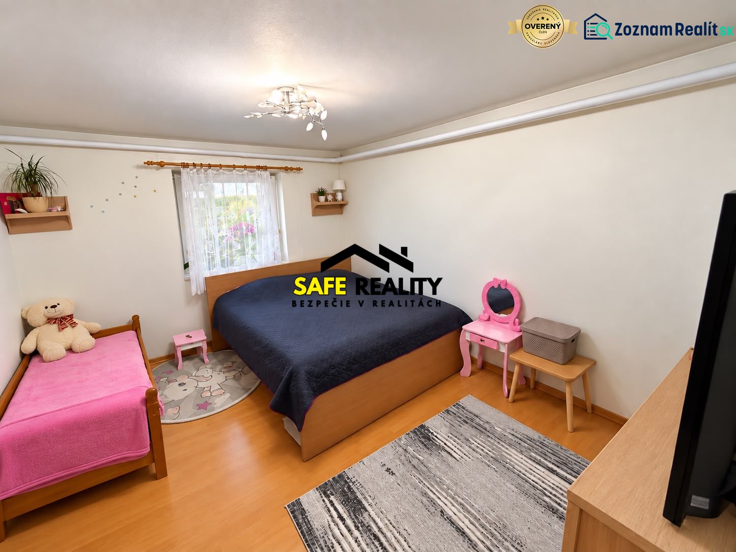 A bedroom with wood-patterned flooring, two beds, and children's furniture in a studio apartment.