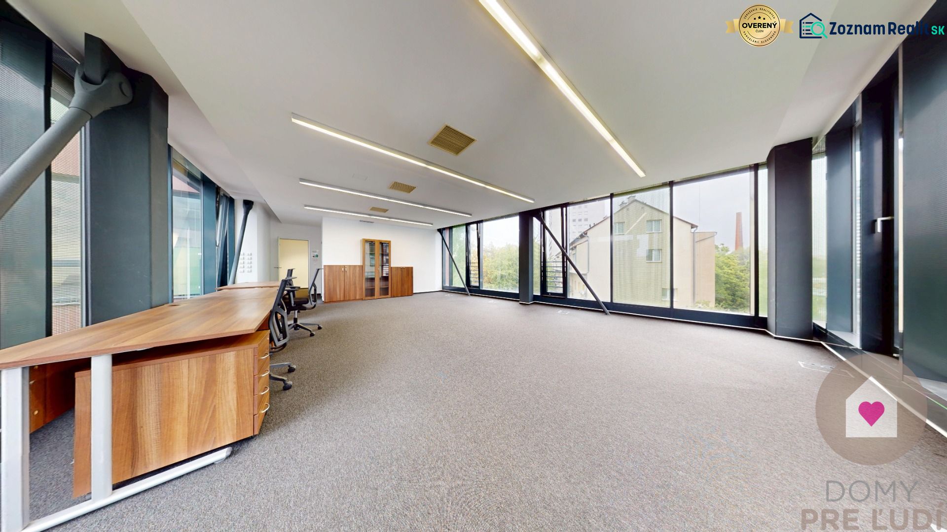Spacious offices with large windows and wooden desks, carpeted floor.