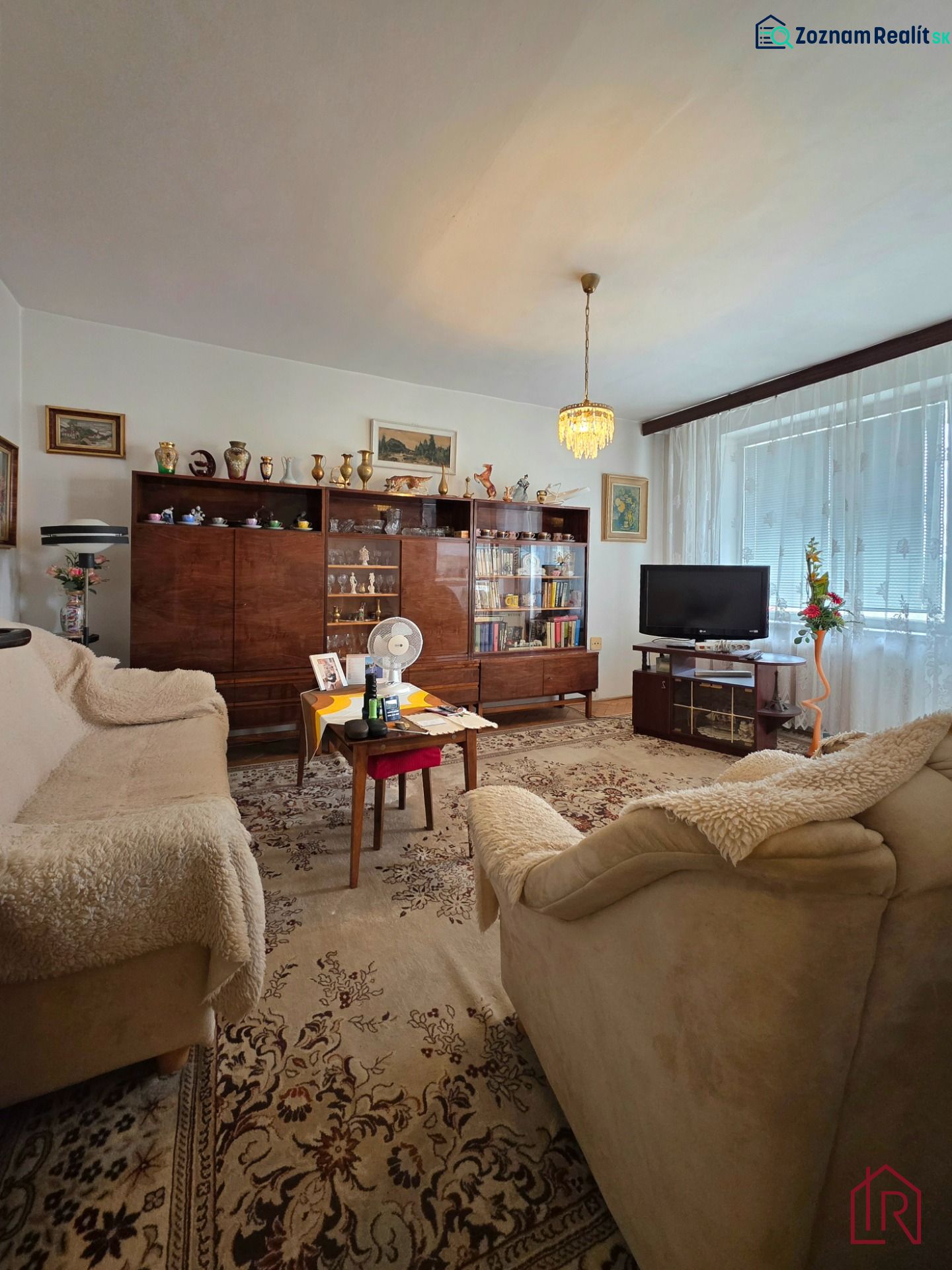 Living room of a 2-room apartment with retro furniture and a floral patterned carpet.