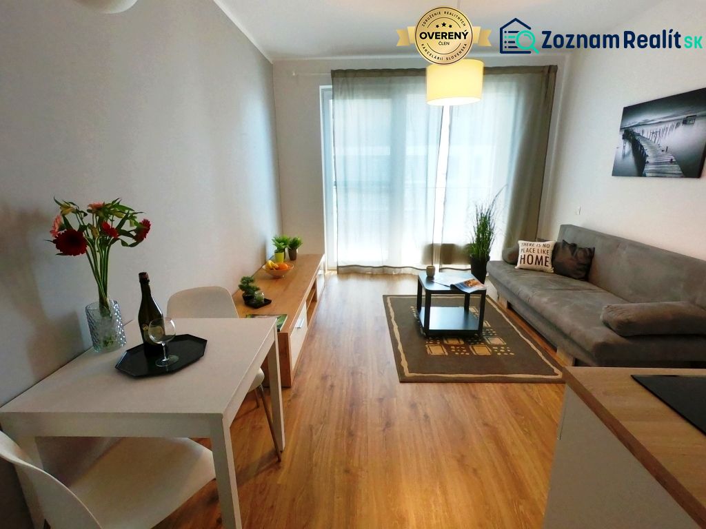 Floor with wooden decor, sofa, table, and dining nook in a studio apartment.