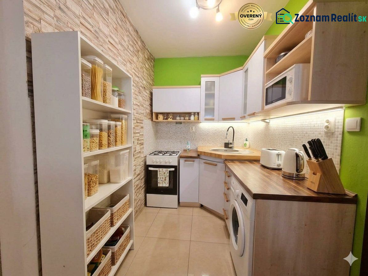 A kitchen in a 2-room apartment with shelves, appliances, and wooden decor on the countertop.