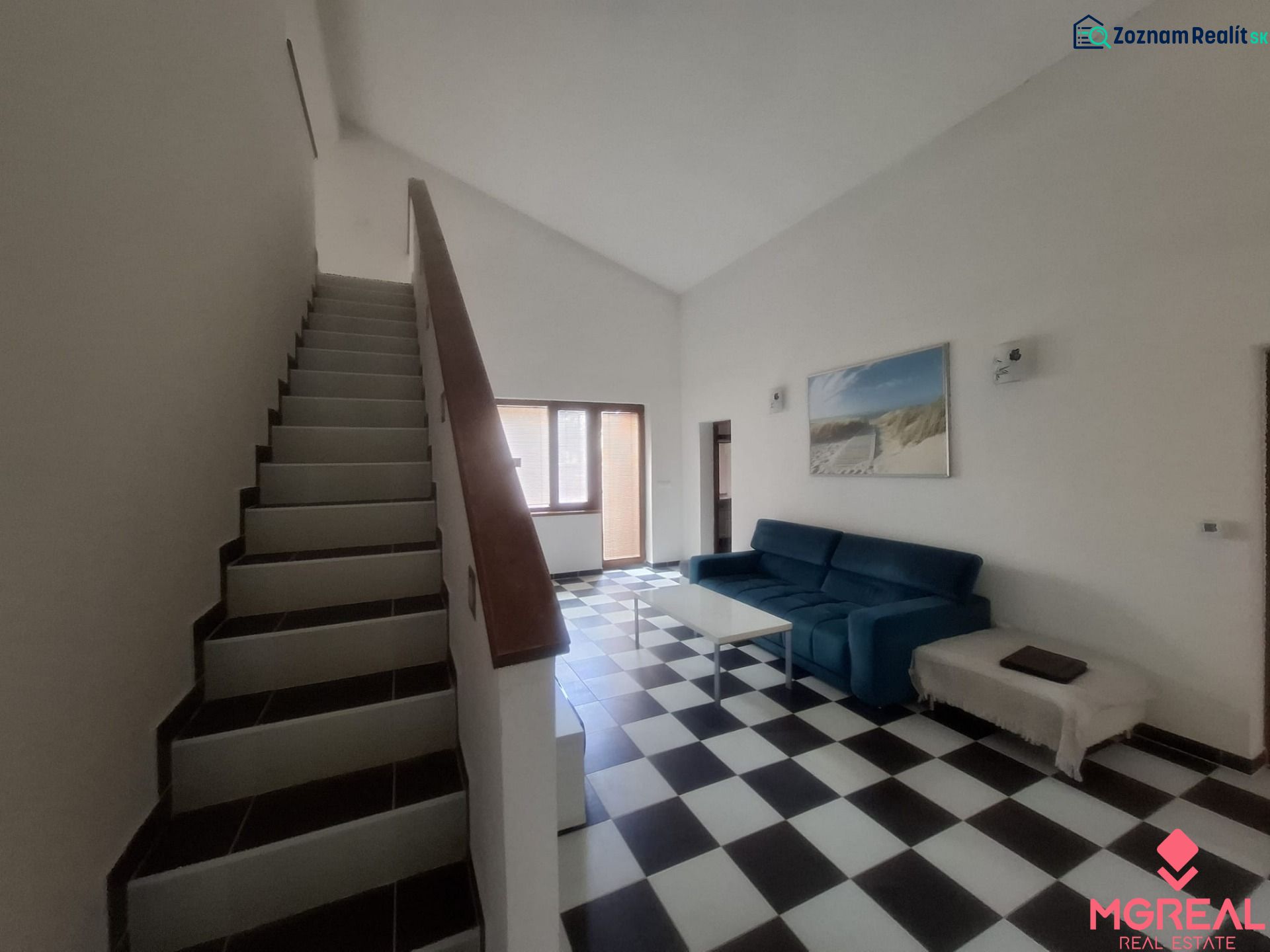 Staircase and living room with black and white flooring in a family house.