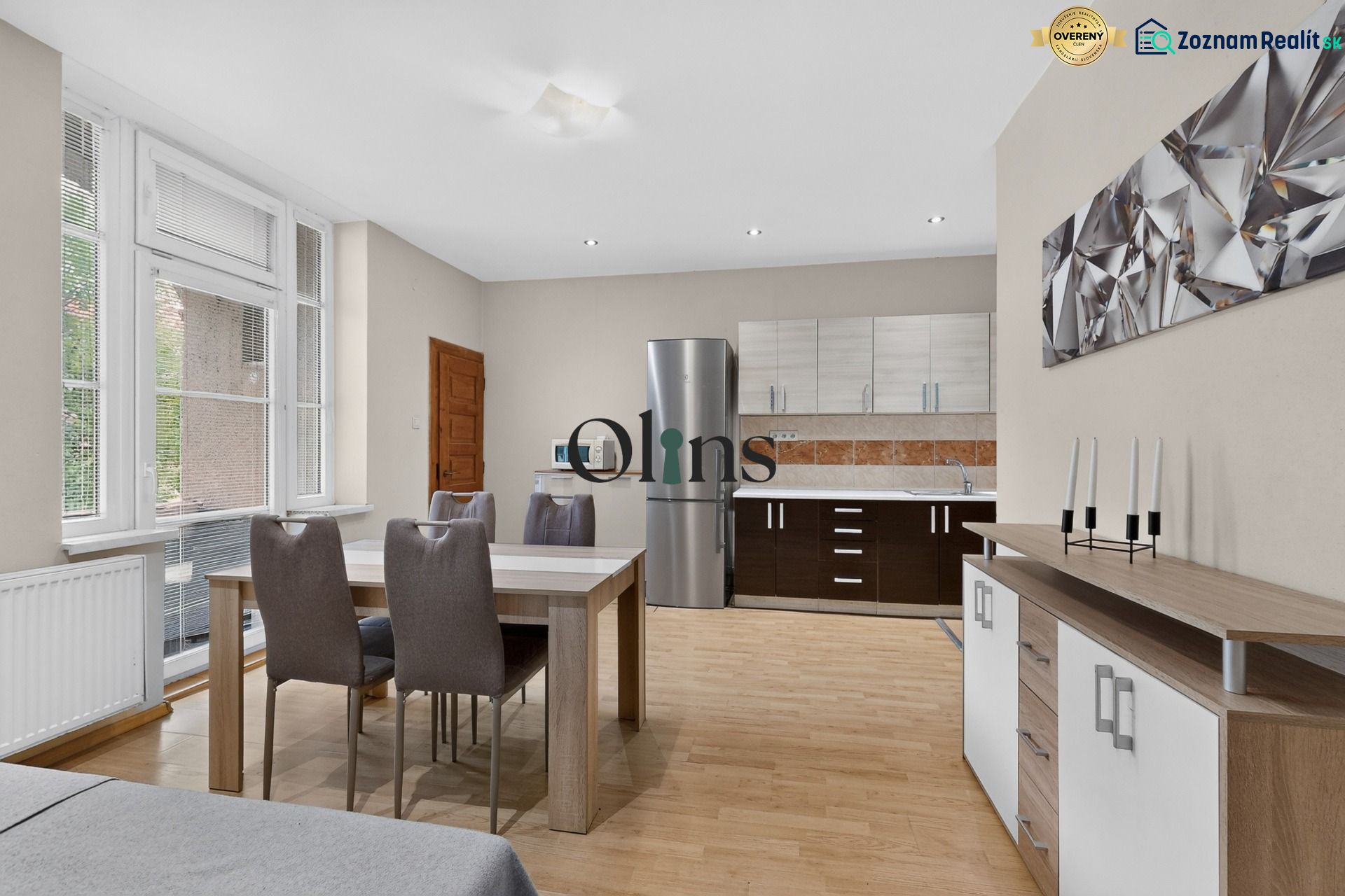 Living space with wood-patterned flooring and a dining area in a three-room apartment.