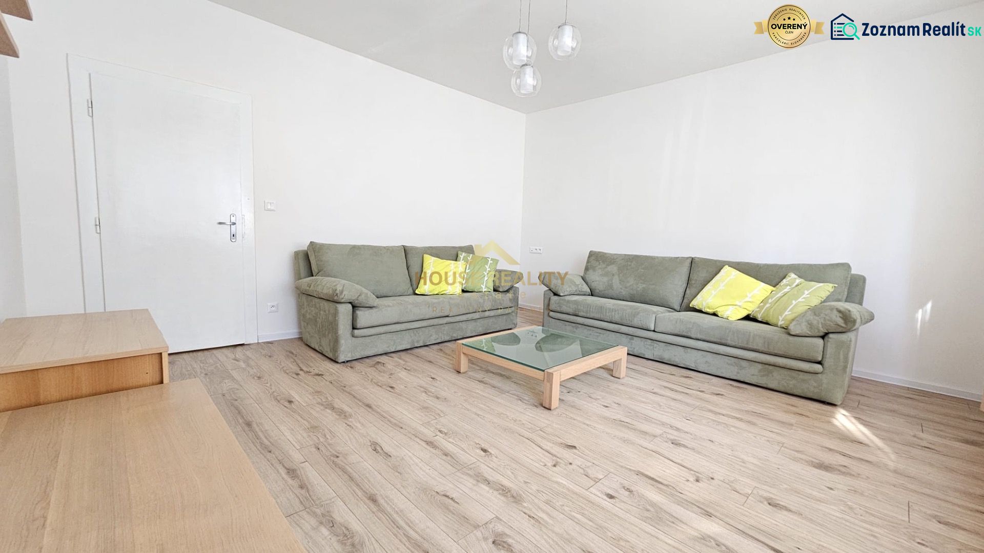 Living room with green sofas, a glass table, and a wooden decor floor.