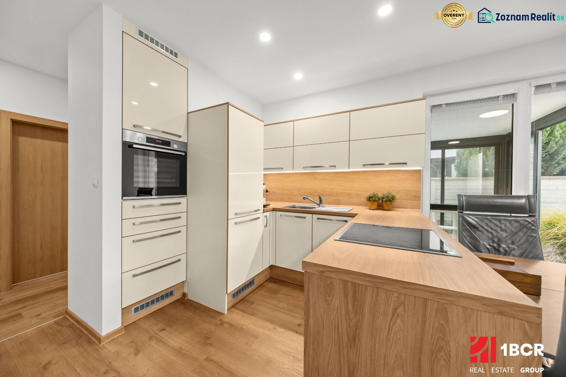 A kitchen in a 3-room apartment with a wooden decor floor and white cabinets.