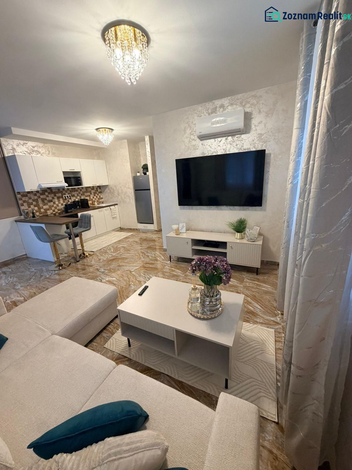 Living room in a 3-room apartment with a TV, sofa, and chandelier.