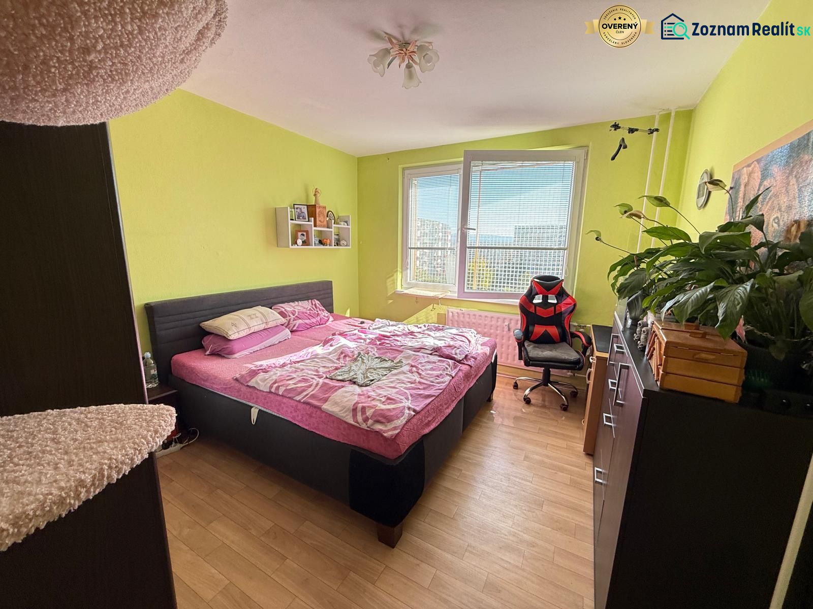 Bedroom in a 2-room apartment with wood-patterned flooring and a comfortable bed.