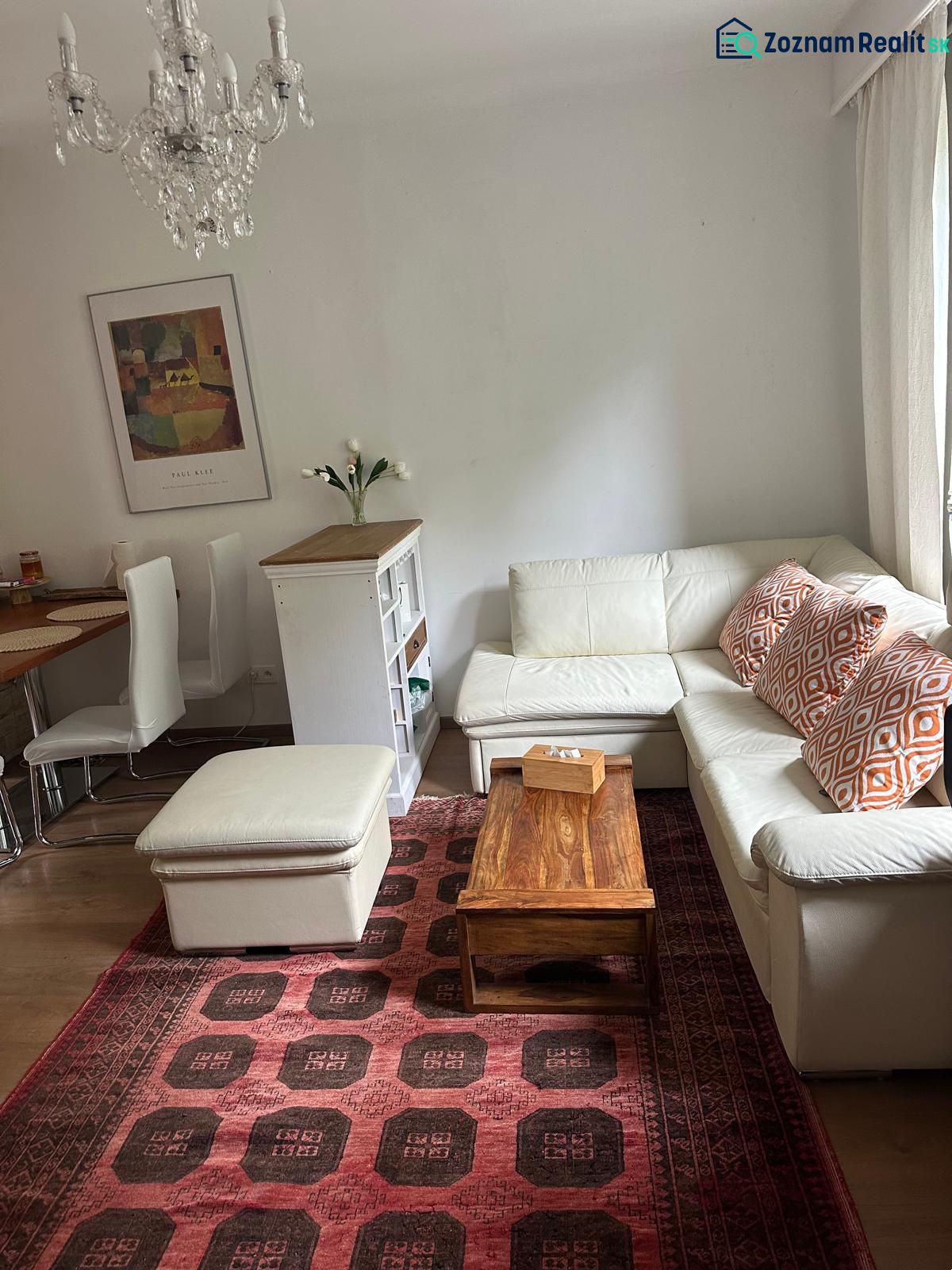 Living room in a three-room apartment with a white sofa and a red patterned carpet.