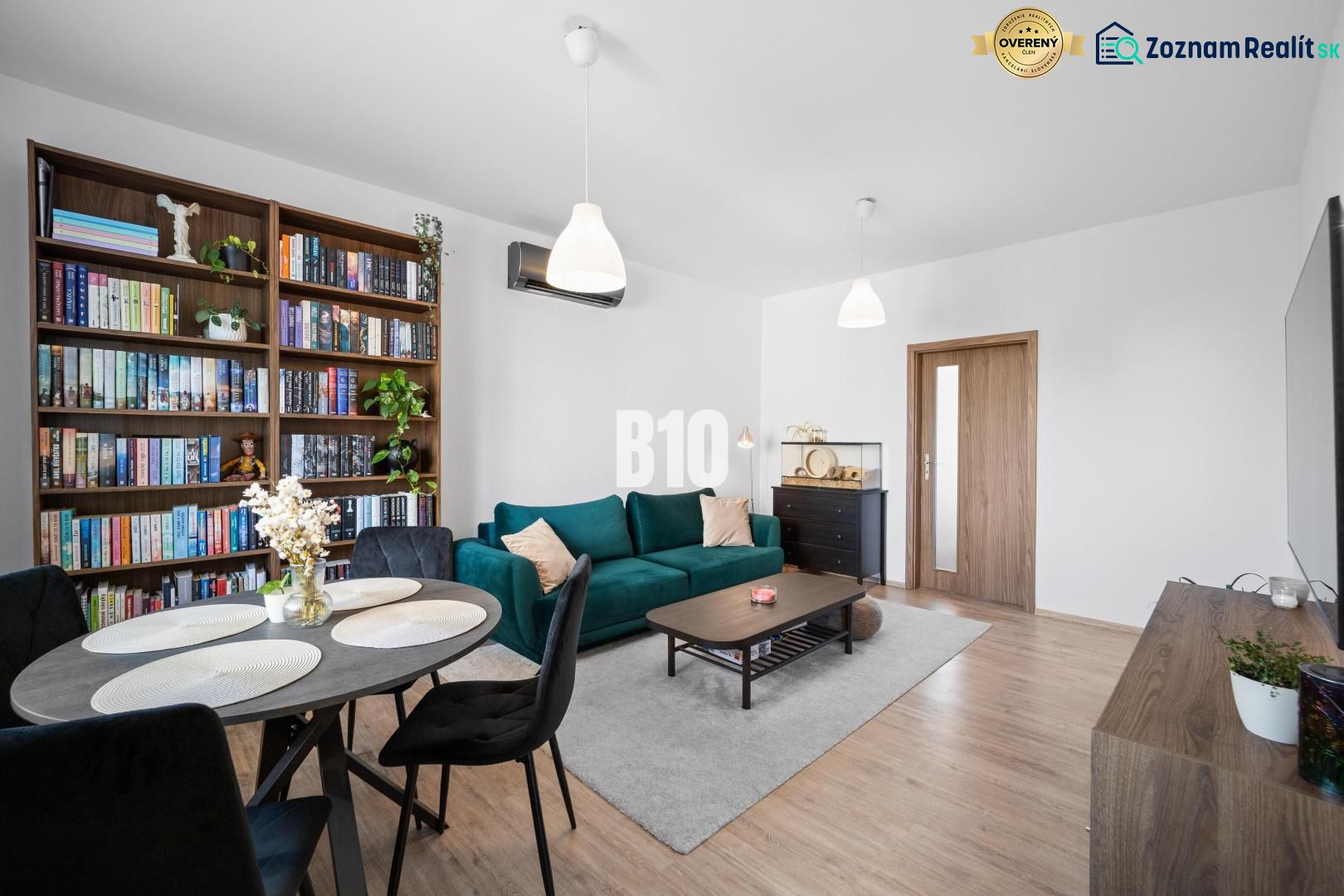 Living room in a two-room apartment with a wooden decor floor and a bookshelf.