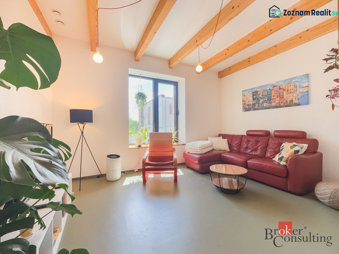 Living room in a 3-room apartment with a red sofa, plants, and wooden beams on the ceiling.