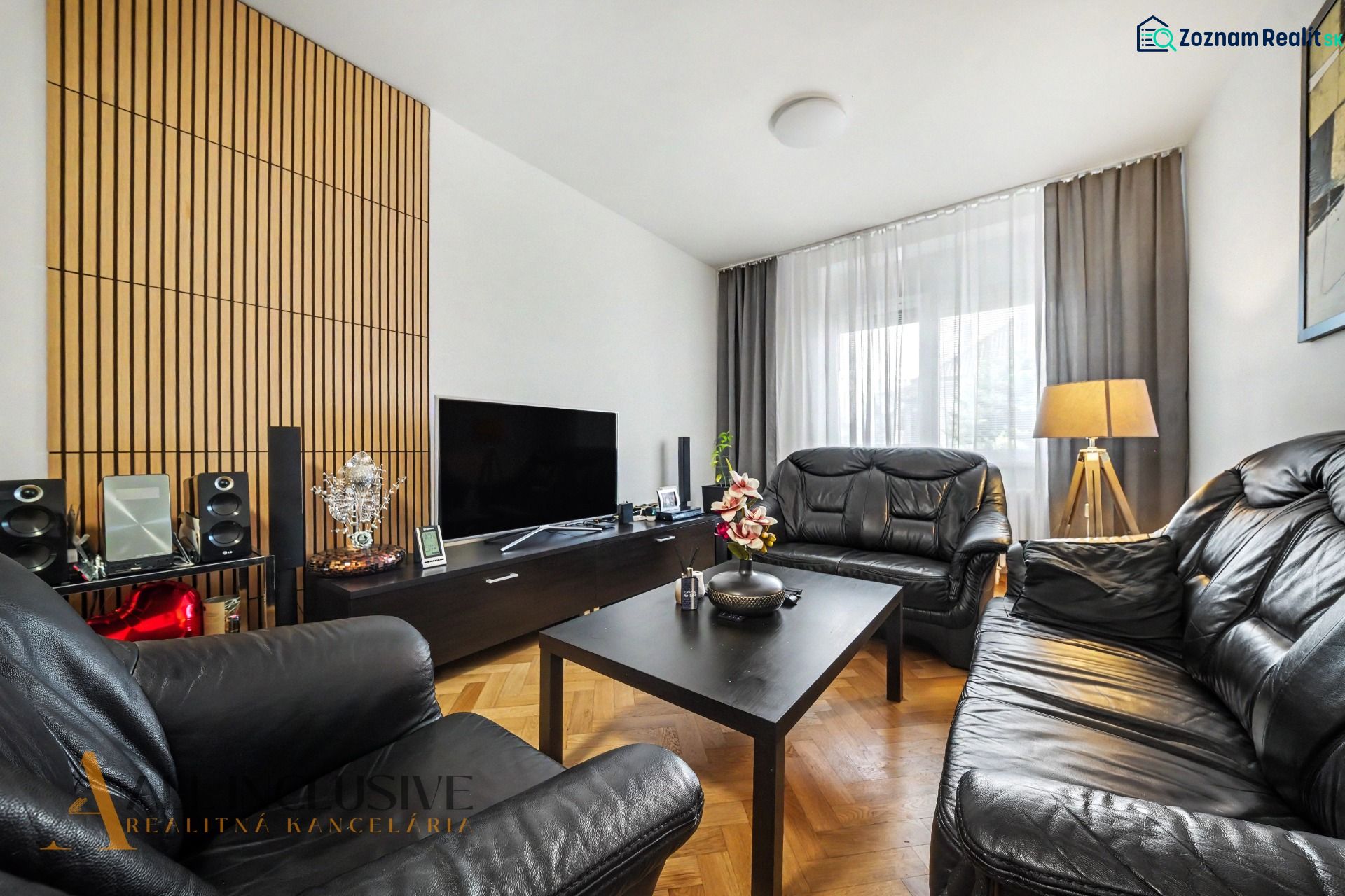Living room of a family house with leather sofas and a wooden-patterned floor.