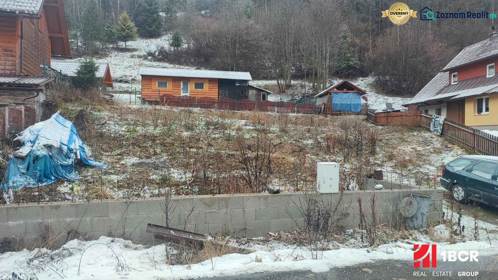 A snowy plot with a family house in Oščadnica surrounded by greenery and wooden structures.