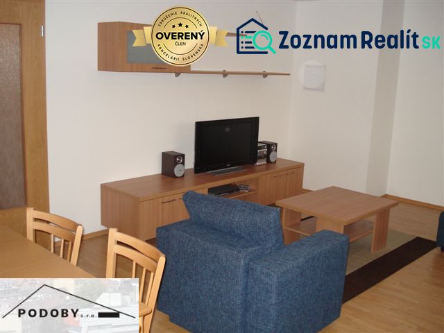 Living room with wood-patterned flooring, blue sofa, and television in a three-room apartment.