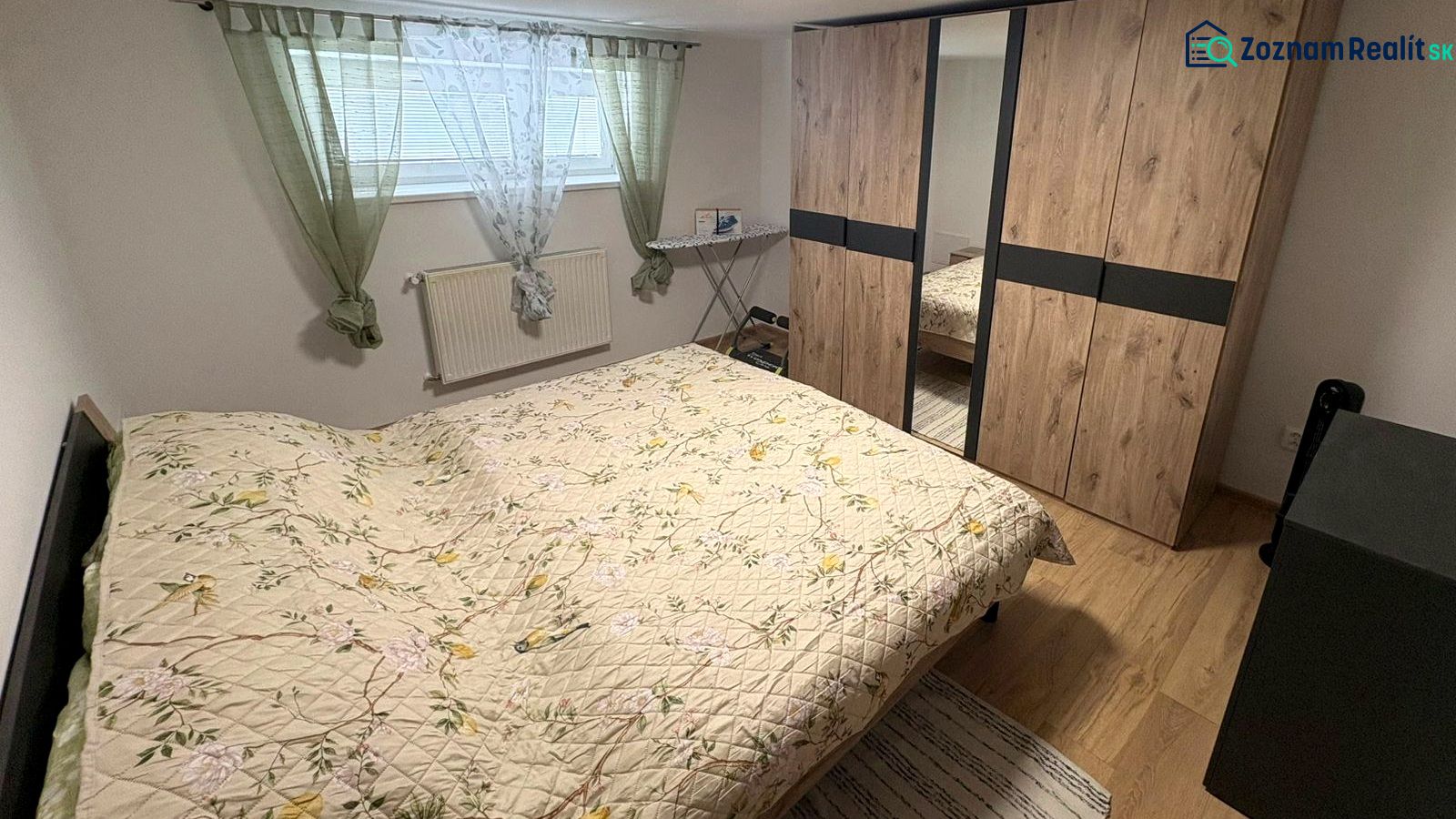 Bedroom in a family house with wood-patterned flooring, built-in wardrobe, and bed.