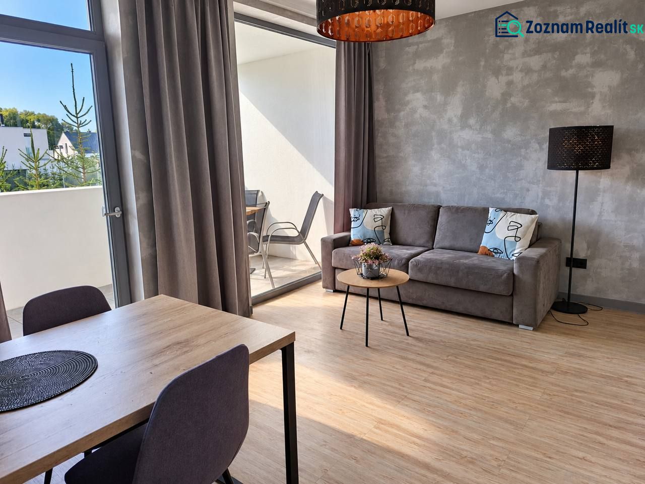 Living room in a two-room apartment with a wooden decor floor and a balcony.