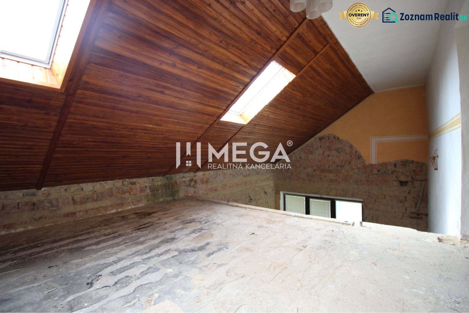 The attic of a family house with wooden roof windows, a brick wall, and light tubes in the roof.