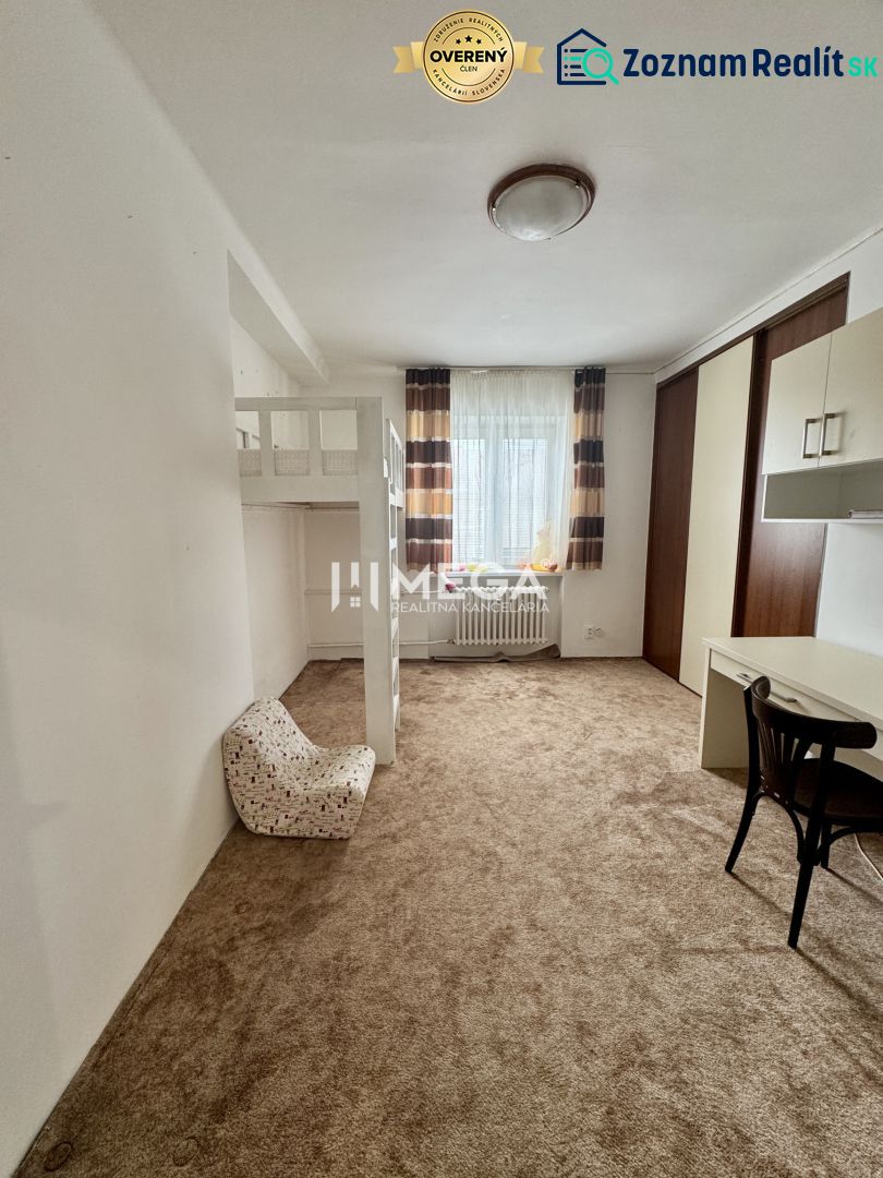 A room with a carpet, a bunk bed, a desk, and a chair in a three-room apartment.