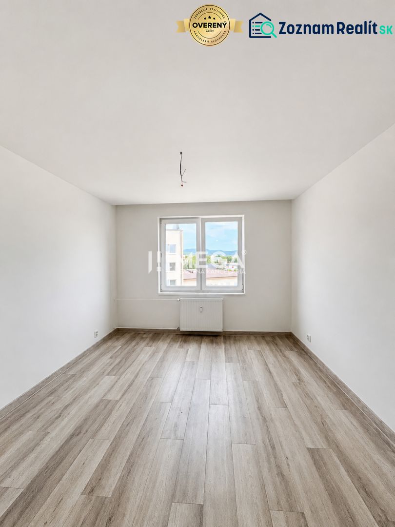 A bright empty space with white walls and a wooden decor floor in a 2-room apartment.