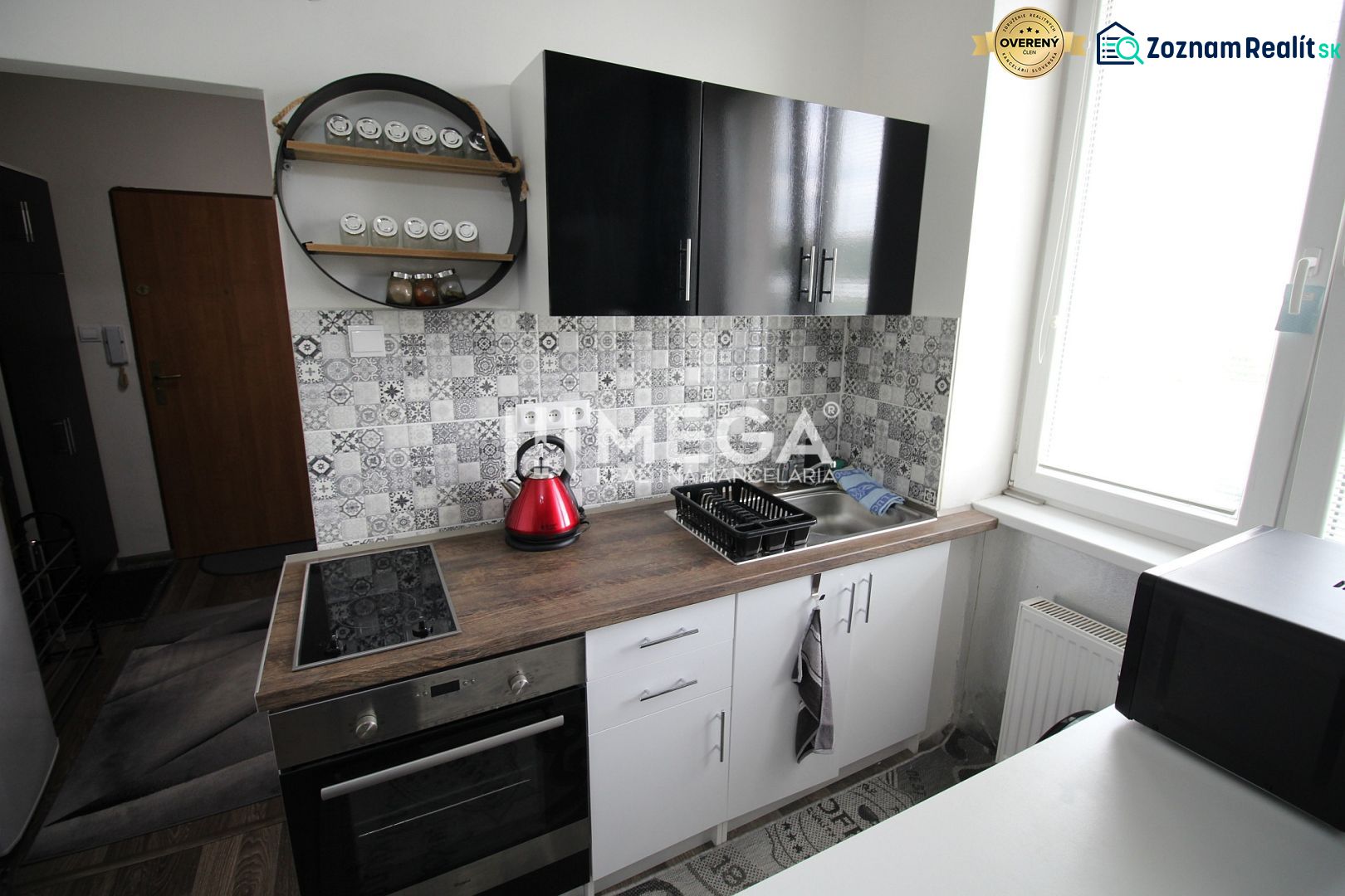 Recreational apartment kitchen with black cabinets, cooktop, and decorative tiles.