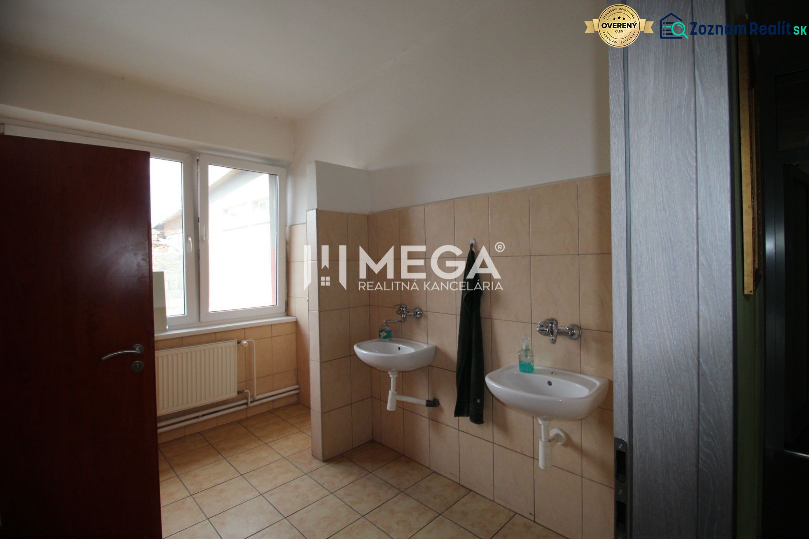 Bathroom in offices with two sinks and a window, butter-cream tiles.