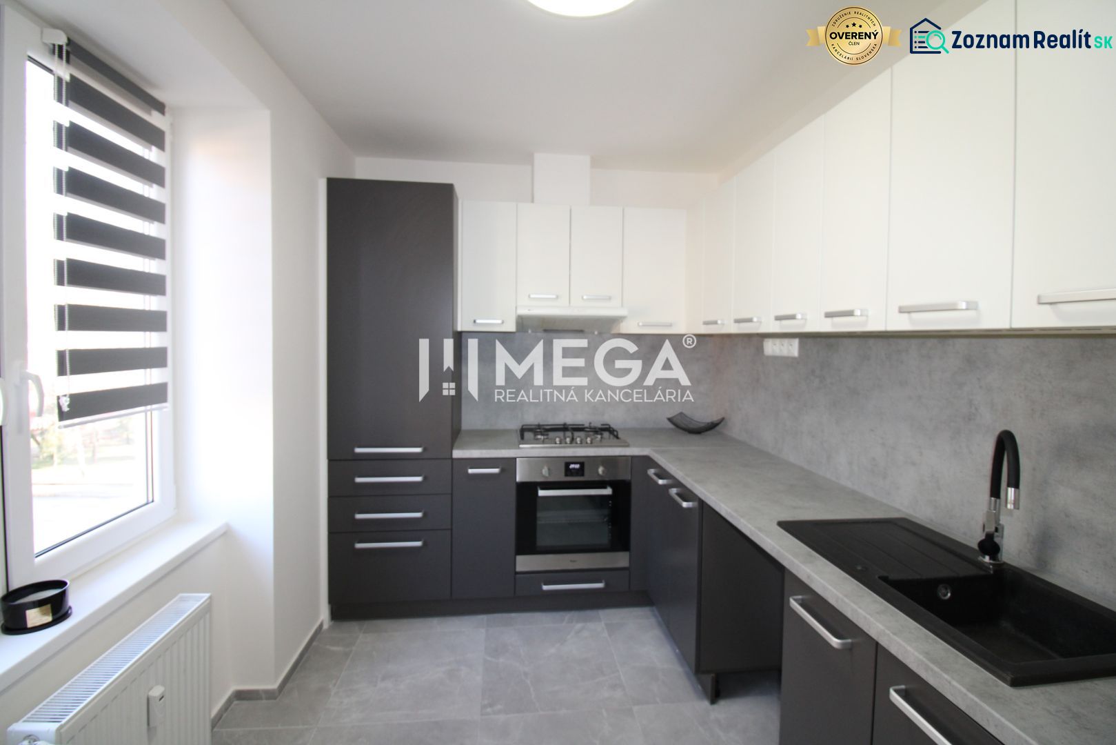 A kitchen in a 2-room apartment with simple cabinets and a gray countertop.