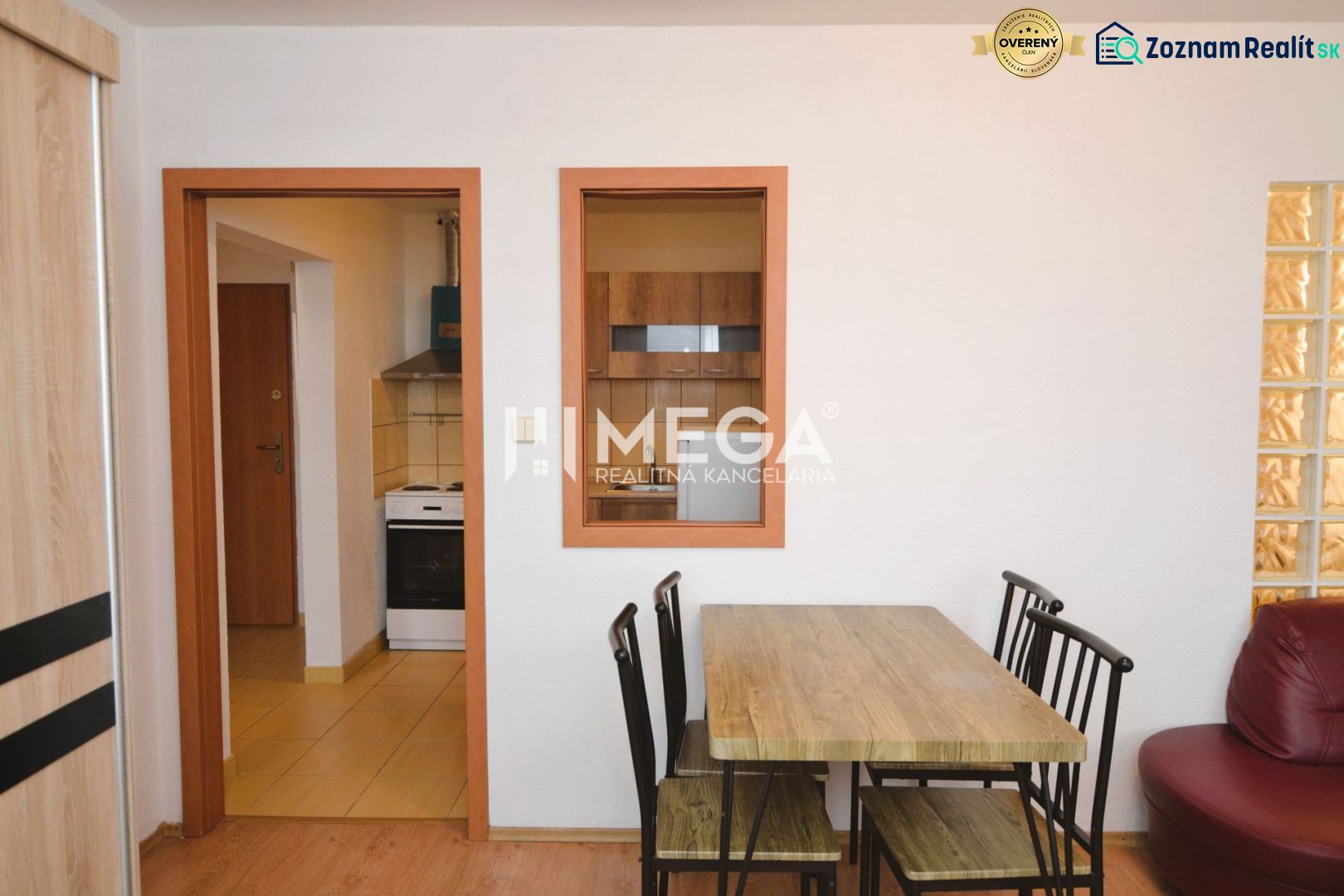 Dining area with wooden decor and a view into the kitchen in a 2-room apartment.