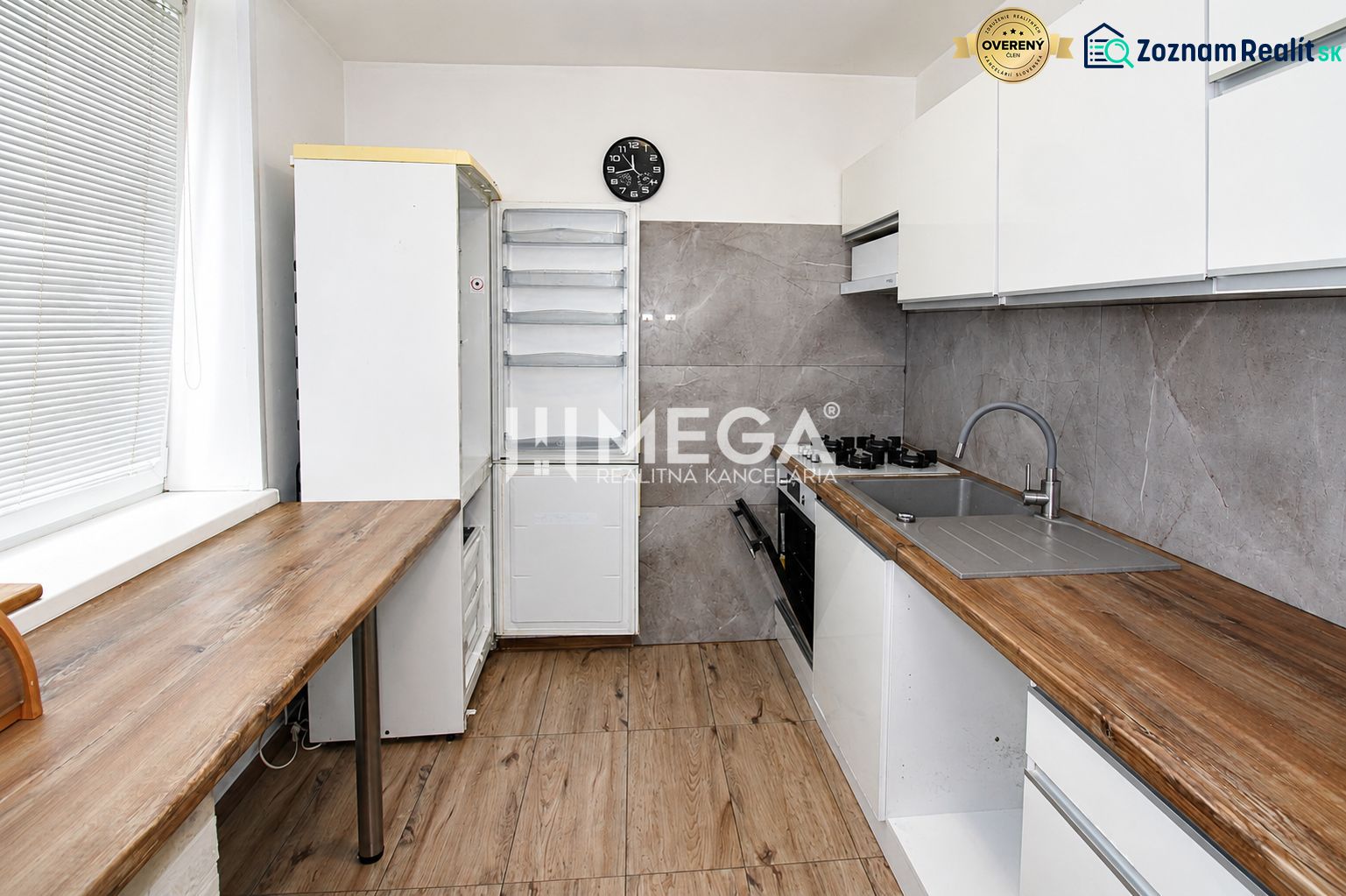 A kitchen in a 3-room apartment with a wooden decor floor and an elegant kitchen unit.