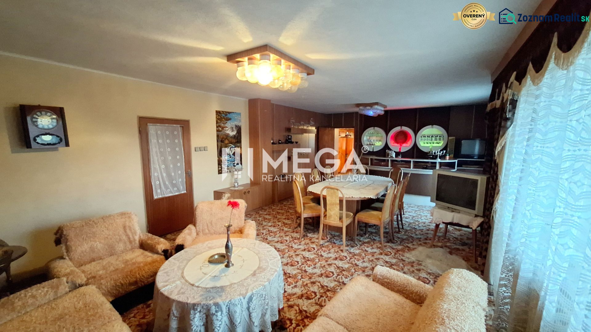 Living room of a family house with carpet flooring, furniture, and decorative curtains.