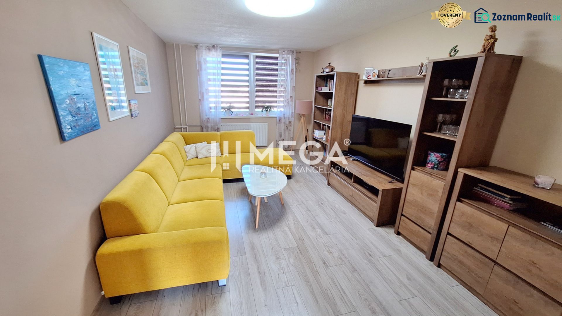 Living room with wood-patterned flooring and a yellow sofa in a three-room apartment.