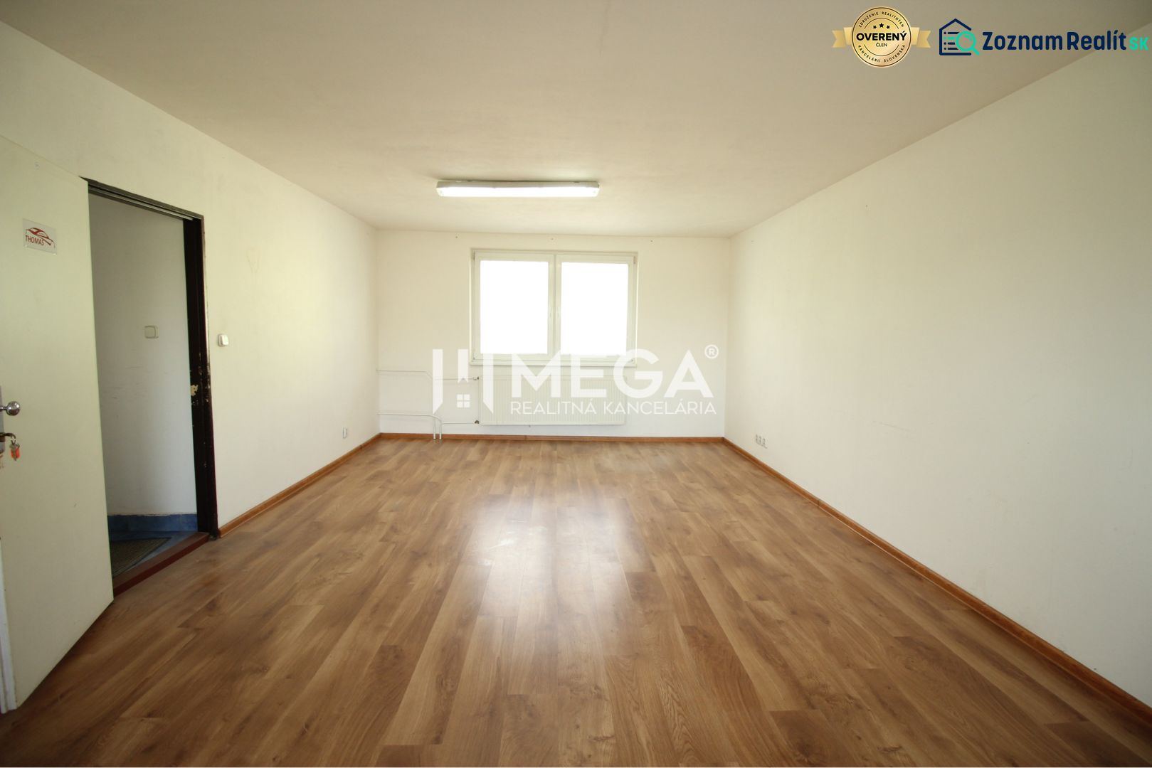 Spacious office with wood-patterned flooring and white walls.