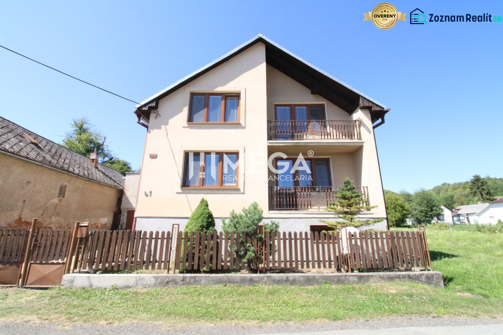 A family house in Nižné Ladičkovce with two balconies and a wooden fence.