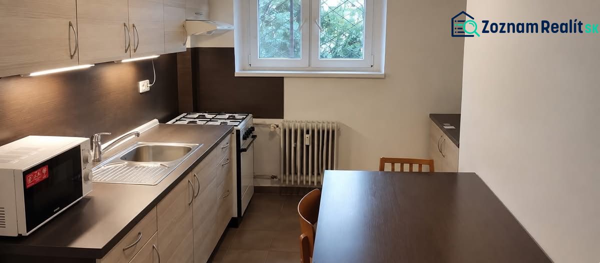 A kitchen in a studio apartment with a gas stove and a microwave on a dark countertop.
