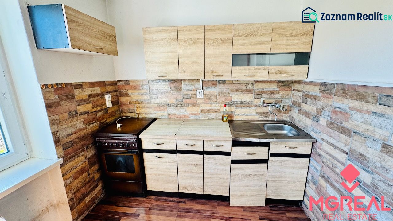 A kitchen in a studio apartment with a wooden decor and stone wall cladding.