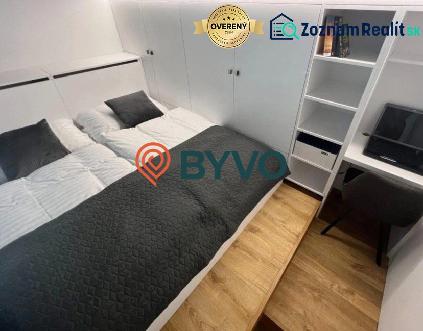 Bedroom in a studio apartment with a double bed and storage space, floor with wooden decor.