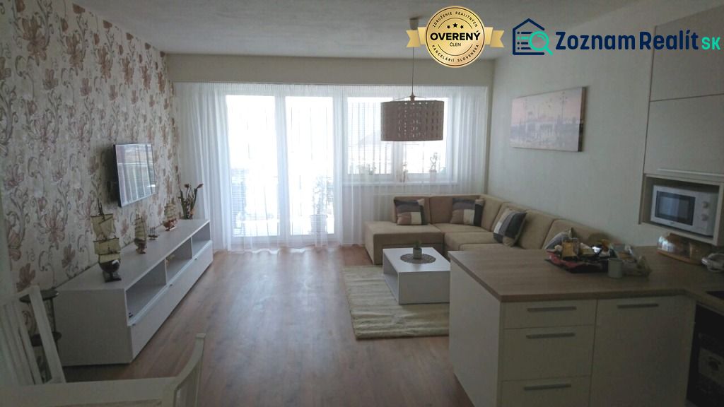 Living room in a three-room apartment with a wooden-patterned floor and floral wallpaper.