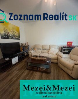 Living room of a two-room apartment with a wood-patterned floor and comfortable seating.