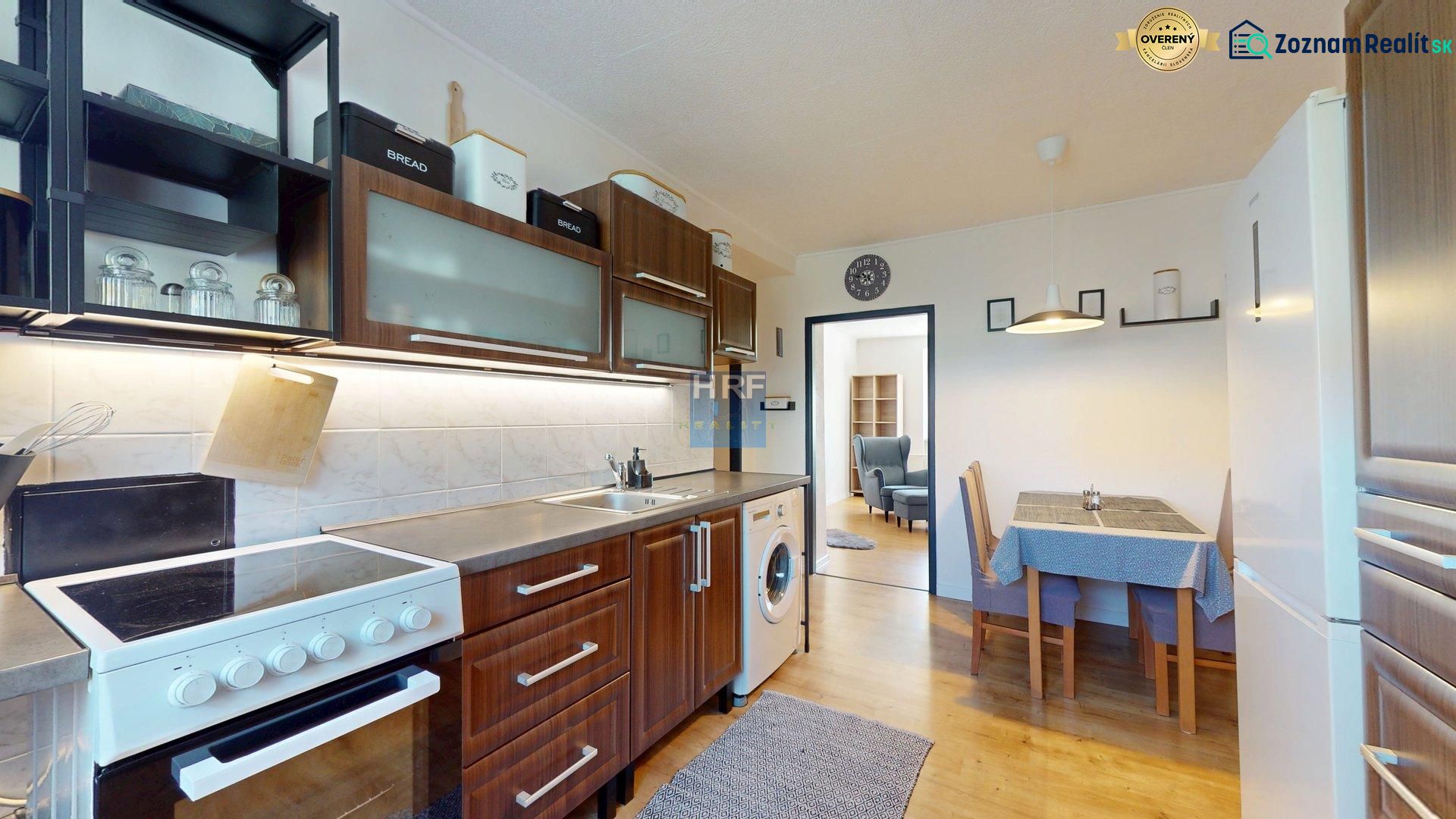 A kitchen in a 2-room apartment with a stove, wooden floor decor, and a dining table.